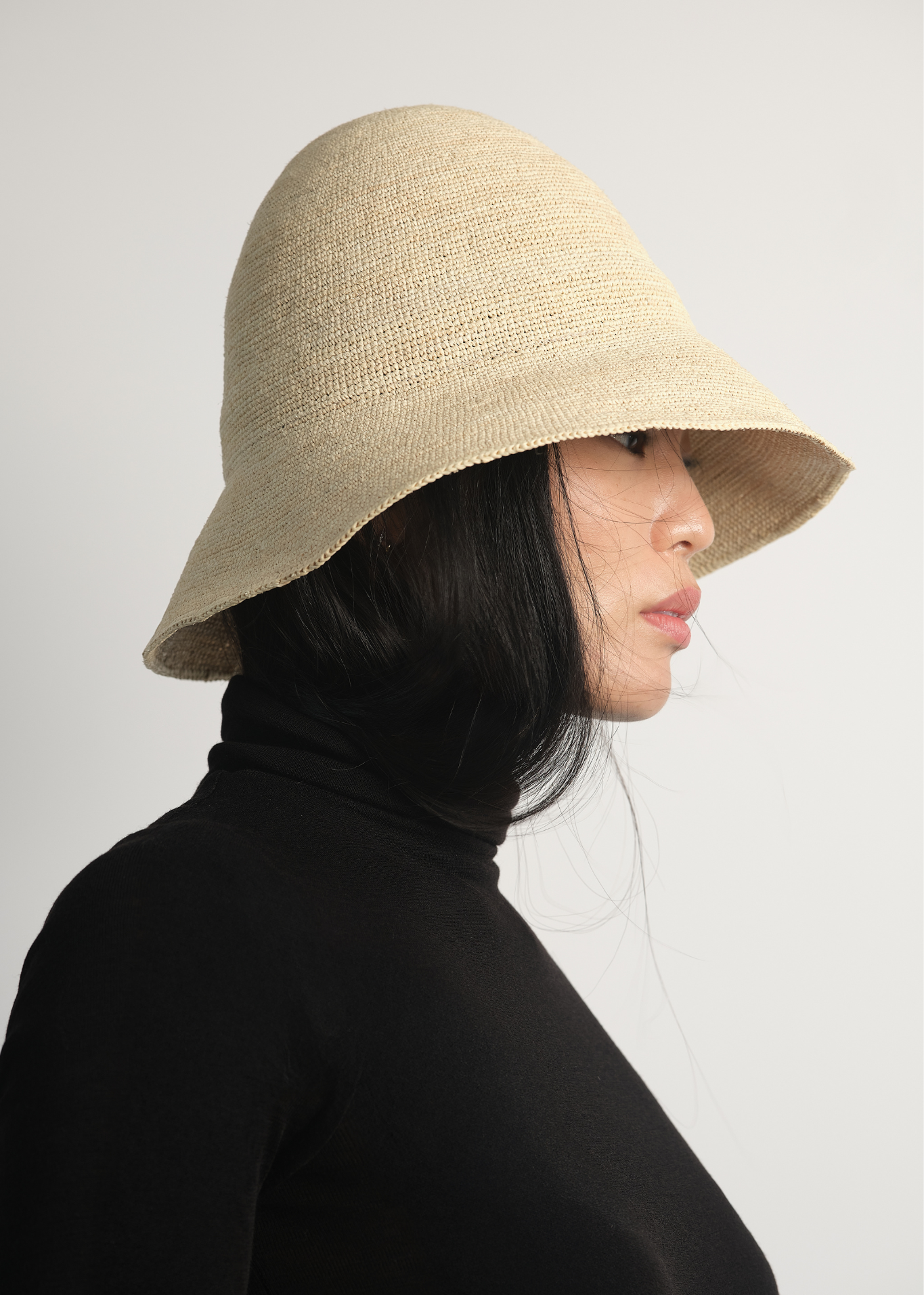 Bucket z rafii w kolorze naturalnym na modelce w czarnym golfie