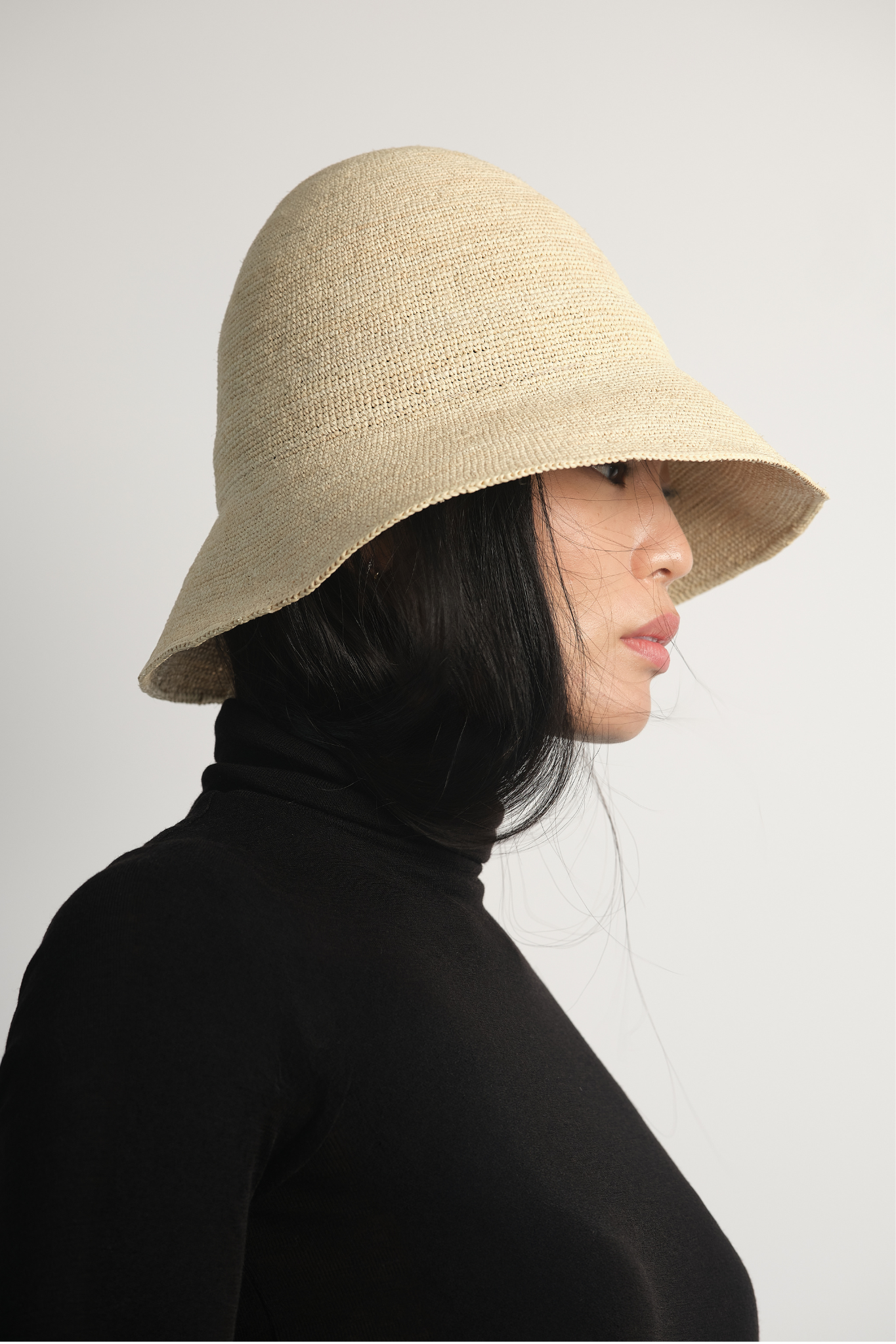 Bucket z rafii w kolorze naturalnym na modelce w czarnym golfie